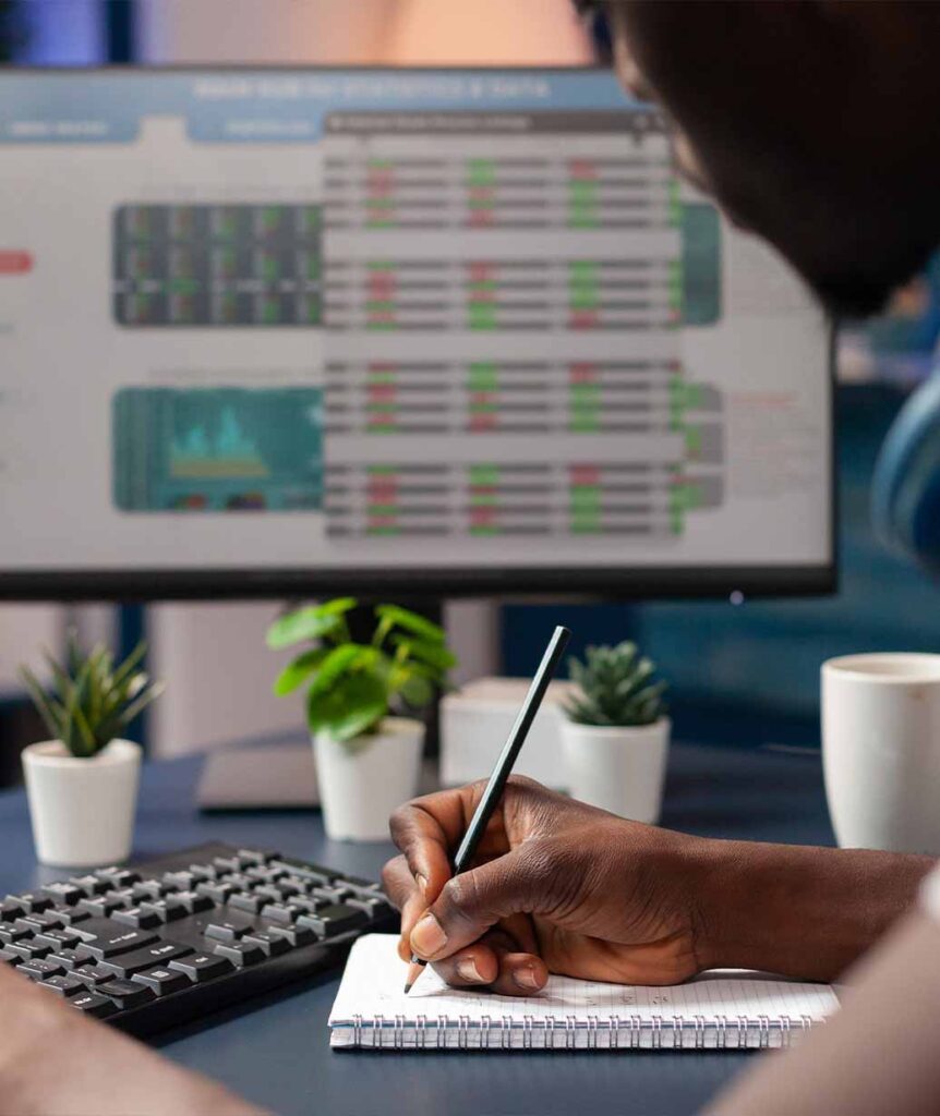 A professional taking notes while reviewing financial charts and technical indicators on a monitor during a momenta training session in Singapore.